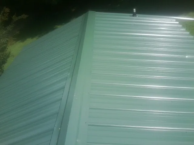New green metal panels meeting at the ridge of a roof — Flat Roof Repair work by our crew in Middleport