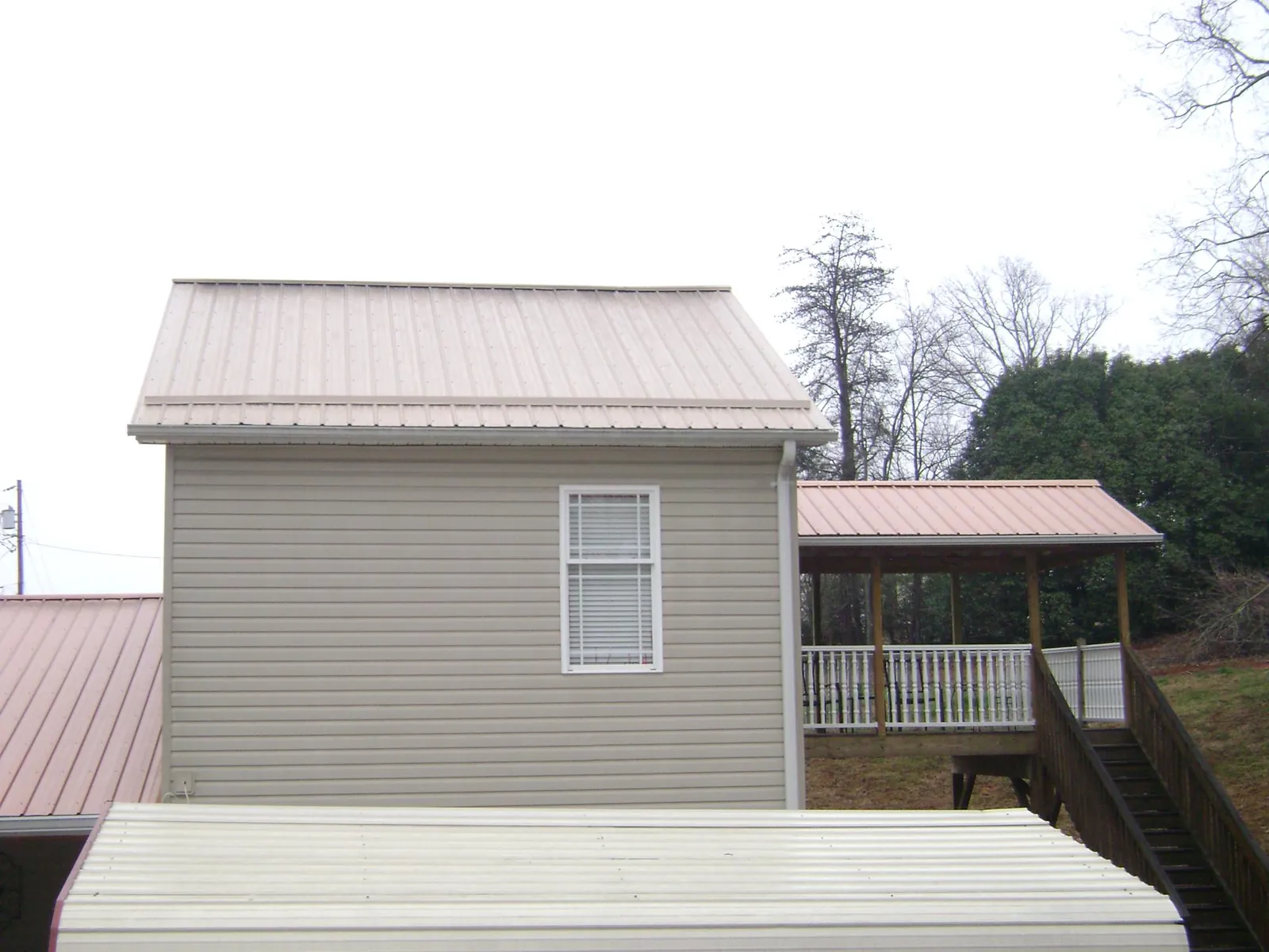 Tan metal roofs on a two story addition and attached porch, from a Roof Replacement job in Middleport